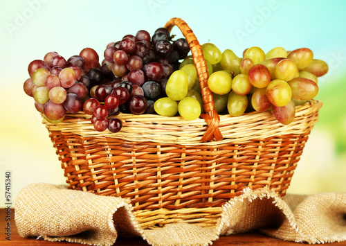 Fresh grape on wicker mat on bright background