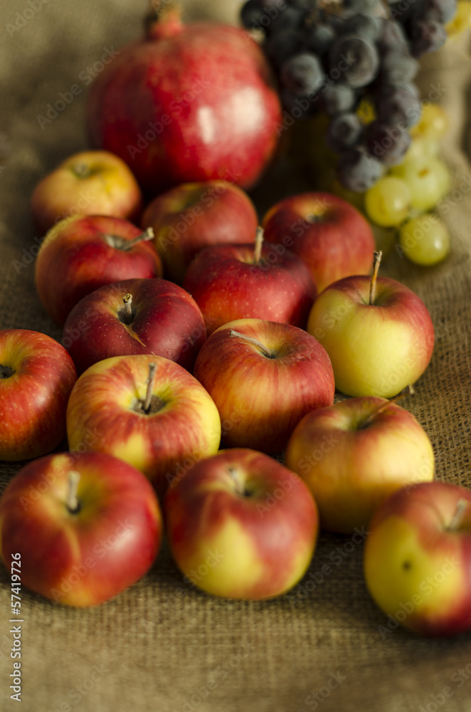 autumn grape, apple, pomegranate fruits on wool sack autumn grape, apple, pomegranate fruits on wool sack