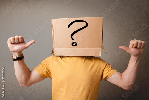 Young man gesturing with a cardboard box on his head with questi photo