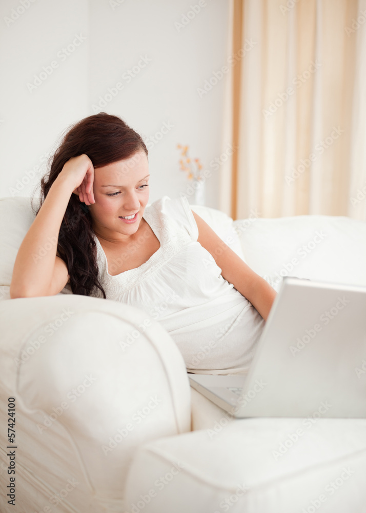 Beautiful red-haired woman relaxing on a sofa surfing the intern Beautiful red-haired woman relaxing on a sofa surfing the intern