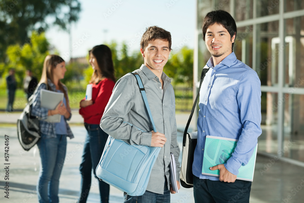 Male Students With Friends Standing In Background On Campus Male Students With Friends Standing In Background On Campus