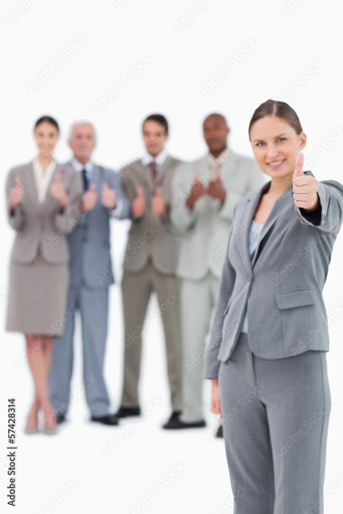 Tradeswoman with thumb up and colleagues behind her Tradeswoman with thumb up and colleagues behind her