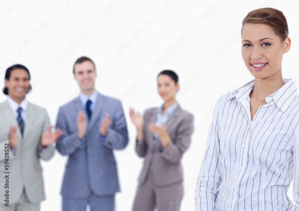 Close-up of a woman smiling with business people applauding whil Close-up of a woman smiling with business people applauding whil