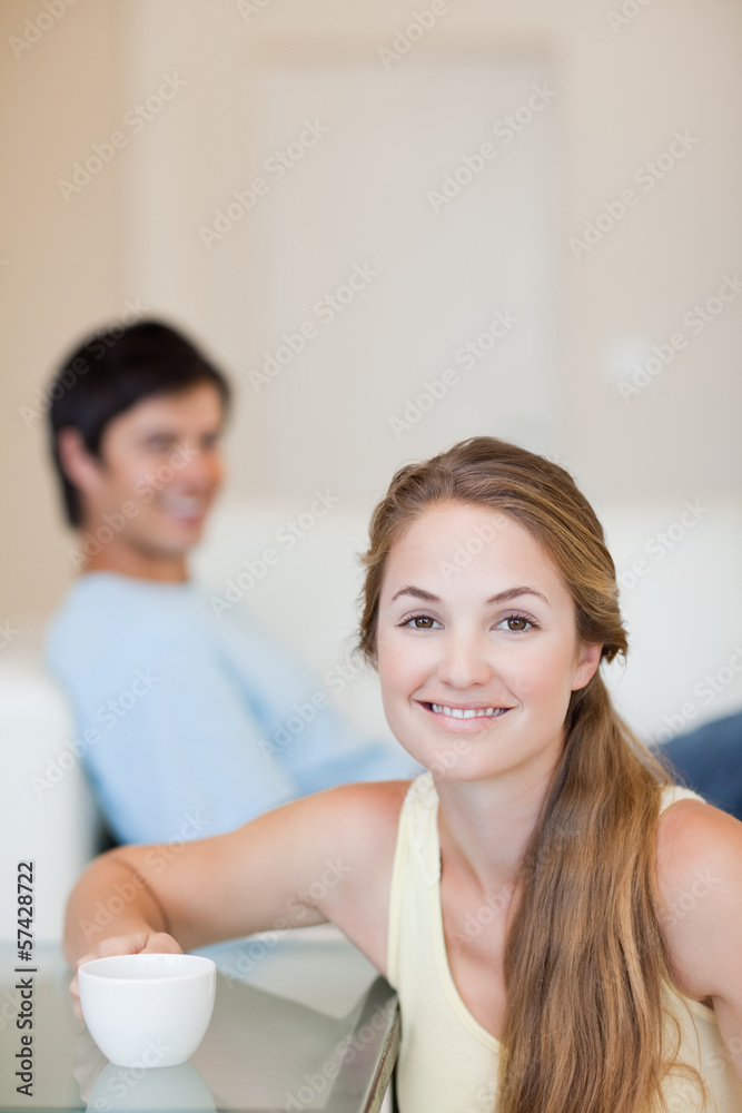 Fototapeta premium Portrait of a woman having a tea while her husband is sitting on