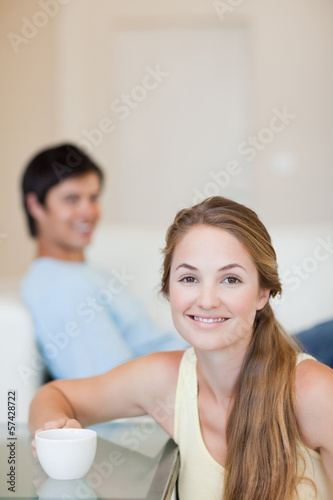 Portrait of a woman having a tea while her husband is sitting on