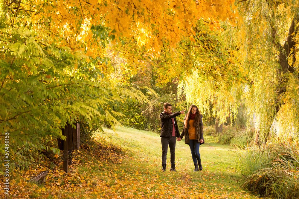 man and woman holding hands walking in the autumn park