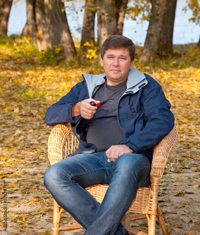 man sitting in a cane chair and smoking a pipe man sitting in a cane chair and smoking a pipe