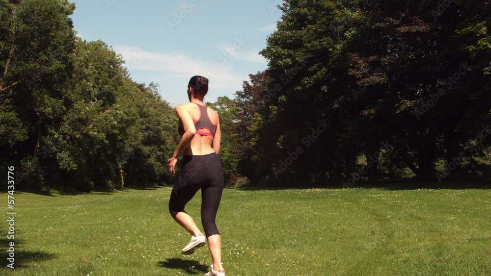 Rear view of sporty woman running on grass Rear view of sporty woman running on grass