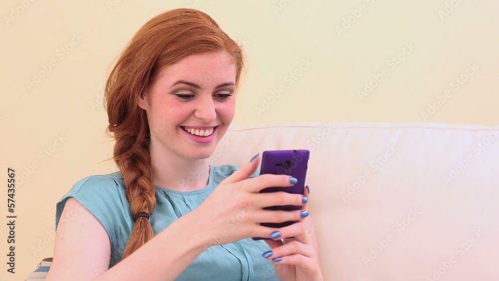 Beautiful brunette sitting on couch using smartphone Beautiful brunette sitting on couch using smartphone
