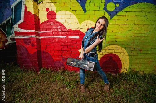 Young girl posing with recorder in front of graffiti photo