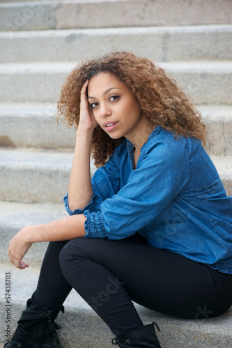 Portrait of an attractive woman with curly hair sitting outdoors