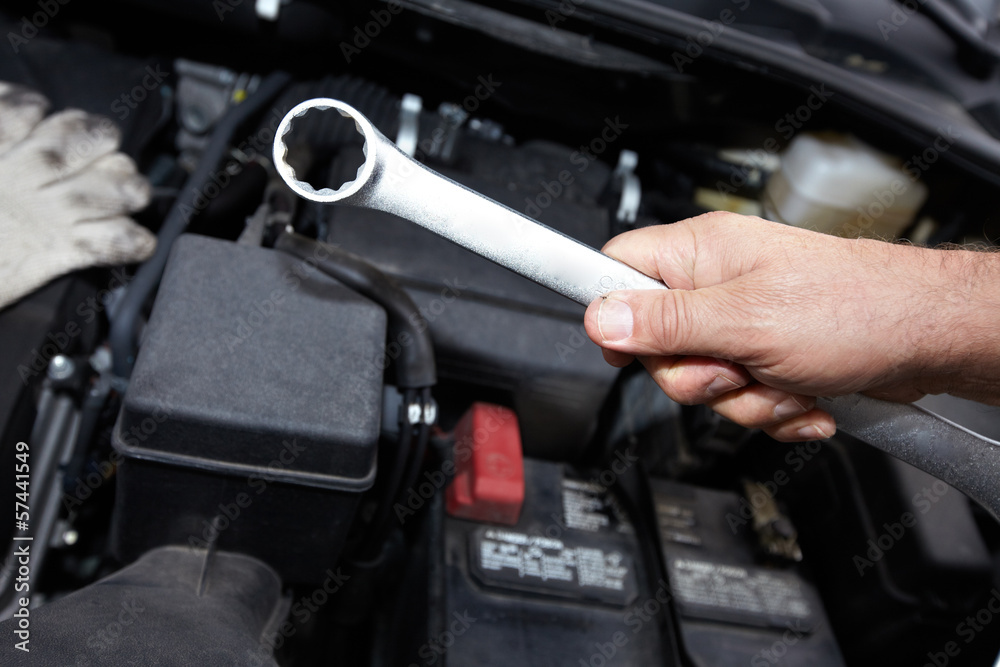 Hands of auto mechanic with wrench.