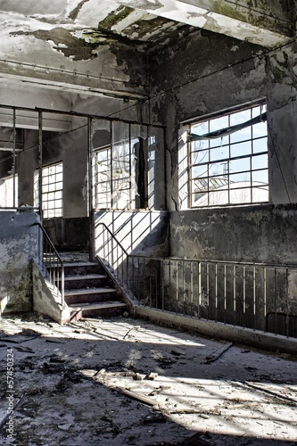 Interior of an abandoned factory, with debris and broken windows