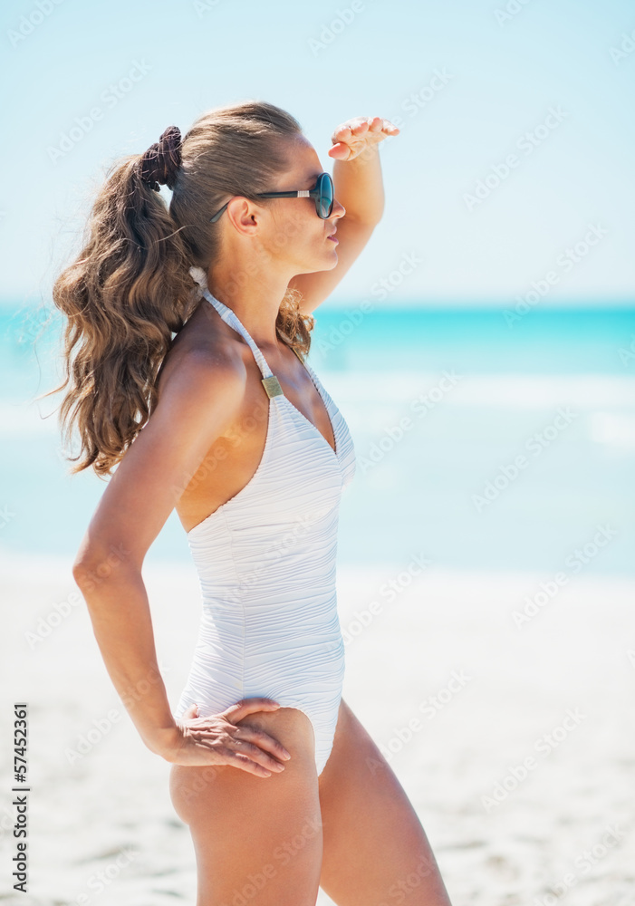 Young woman in swimsuit and sunglasses on beach 