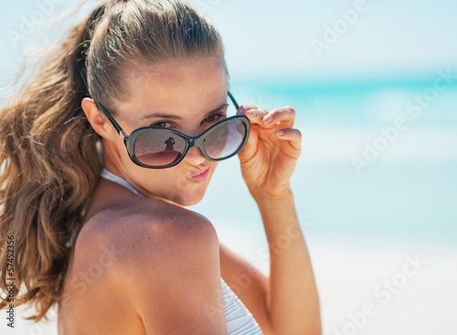 Portrait of young woman in swimsuit on beach making funny face