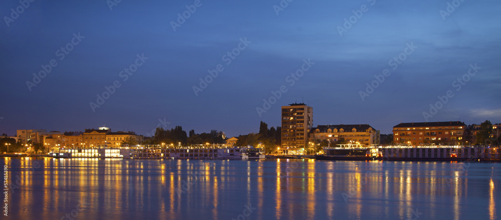 Panorama of Novi Sad quay at night with many ships docked.