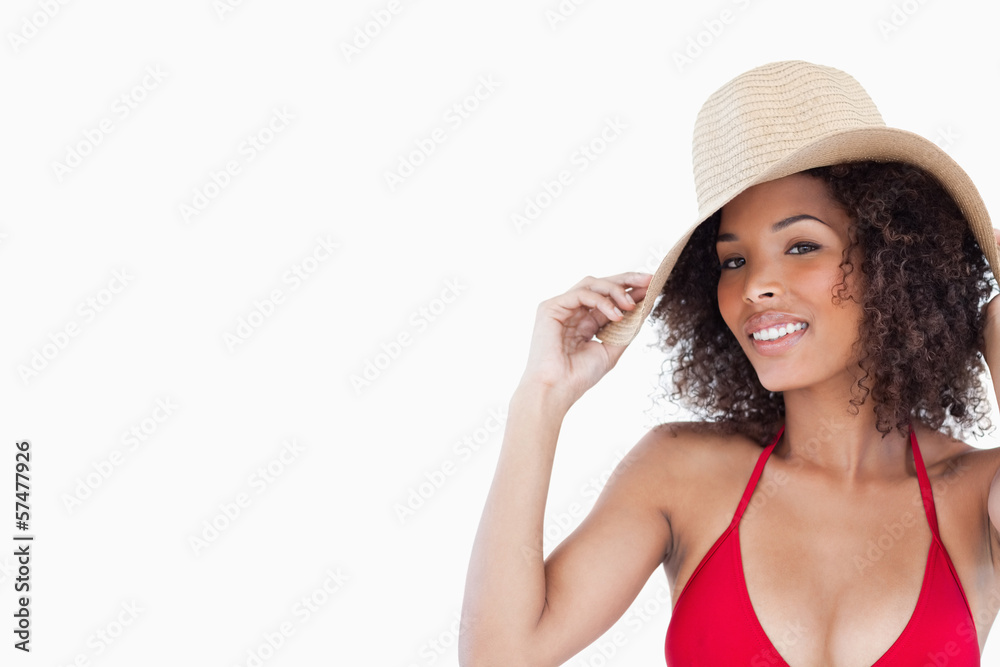 Smiling woman looking at the camera while holding her straw hat Smiling woman looking at the camera while holding her straw hat
