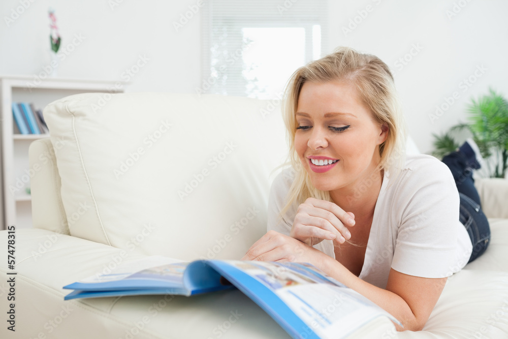 Casual woman lying and reading a booklet Casual woman lying and reading a booklet