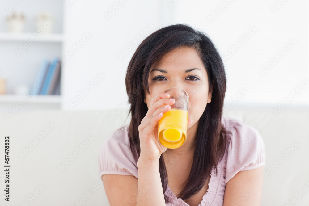 Woman smiling while drinking a glass of orange juice Woman smiling while drinking a glass of orange juice