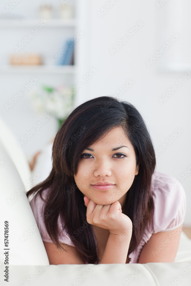 Woman holding her head with her fist while resting on a couch Woman holding her head with her fist while resting on a couch