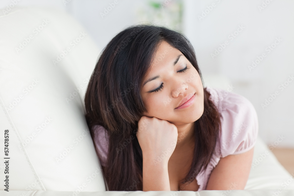 Woman closing her eyes while resting on a couch Woman closing her eyes while resting on a couch