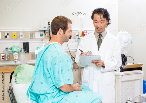 Doctor Discussing Medical Report With Patient In Hospital