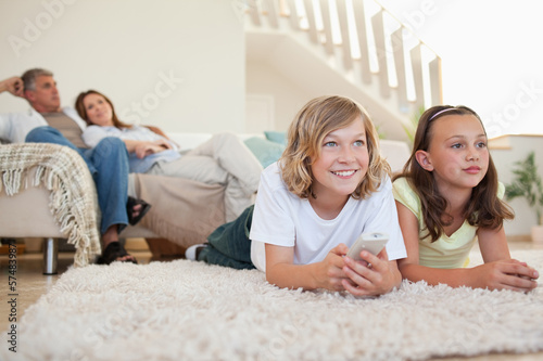 Siblings lying on the carpet watching tv