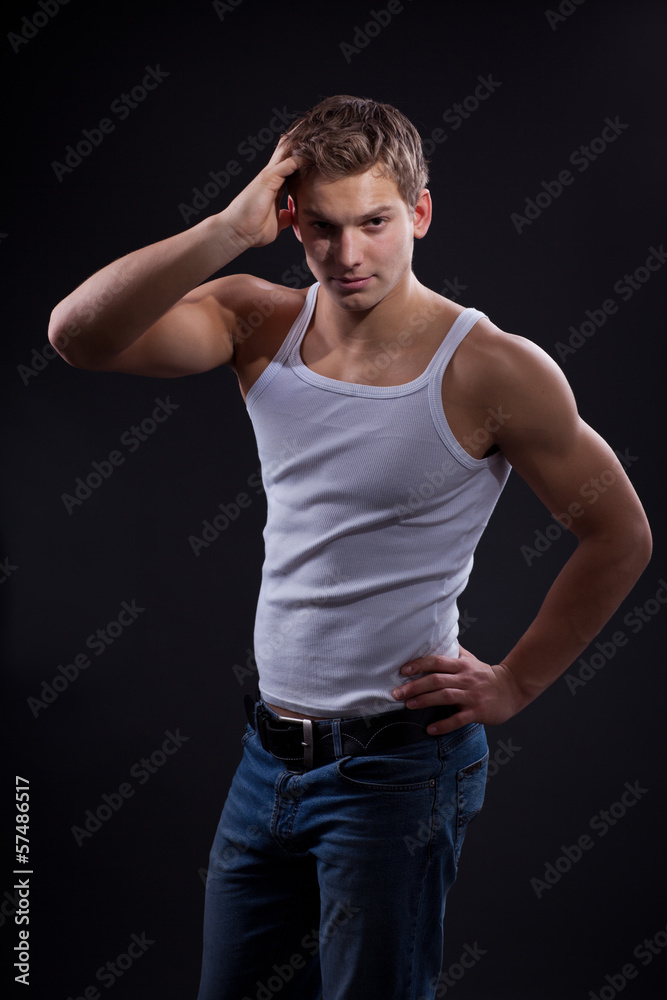 Sexy young man wearing white undershirt and jeans, posing over d Sexy young man wearing white undershirt and jeans, posing over d