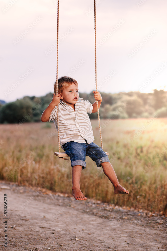 Happy young boy playing on swing in a park Happy young boy playing on swing in a park