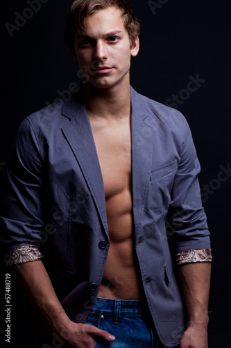 Young sexy macho man with open jacket over dark background © MaxFrost