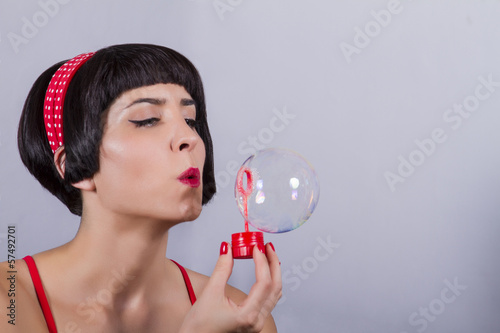 View of a pin-up girl in bikini blowing soap bubbles.