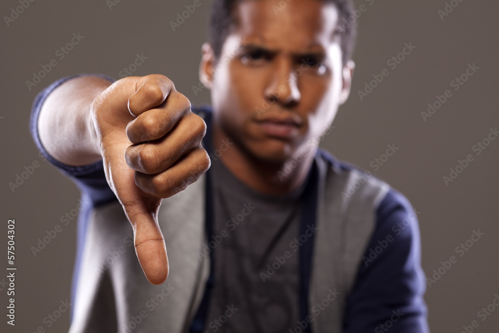 scowling dark young man showing thumb down