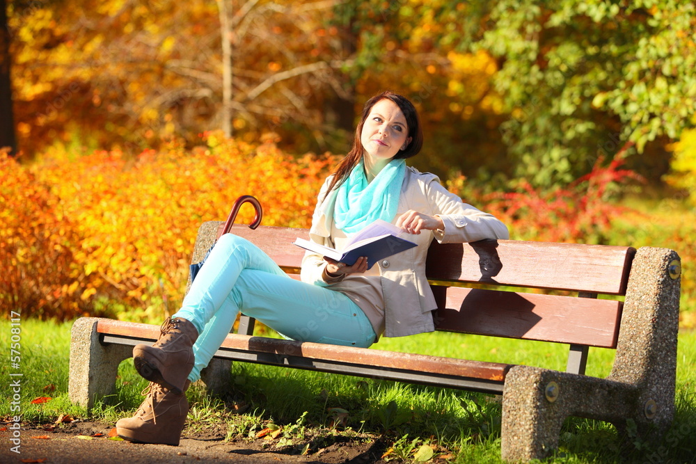 Young girl relaxing in autumnal park reading book Young girl relaxing in autumnal park reading book