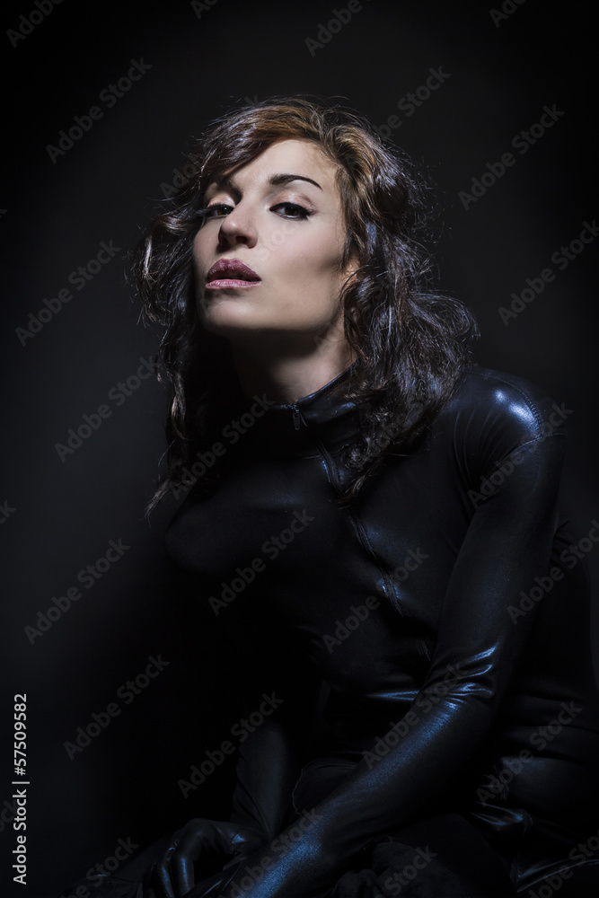 Beautiful brunette woman wearing latex dress on dark background Beautiful brunette woman wearing latex dress on dark background