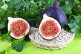 Ripe figs in leaves on wooden table close-up
