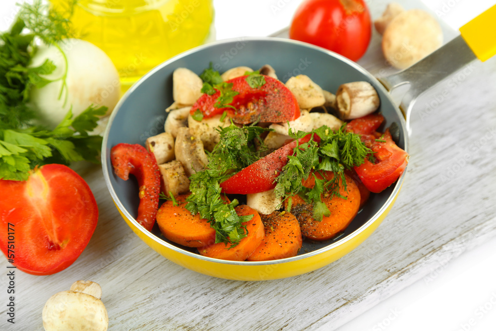 Sliced fresh vegetables in pan on wooden board isolated on Sliced fresh vegetables in pan on wooden board isolated on