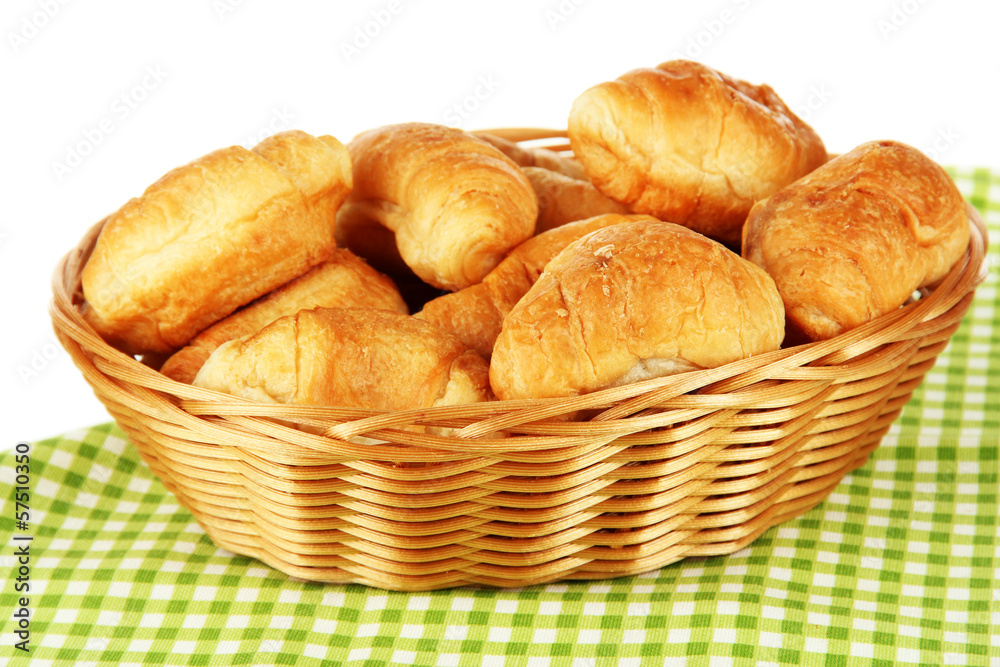 Tasty croissants in wicker basket on table on white background