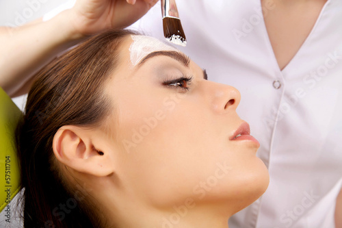 young woman getting beauty skin mask treatment on her face with