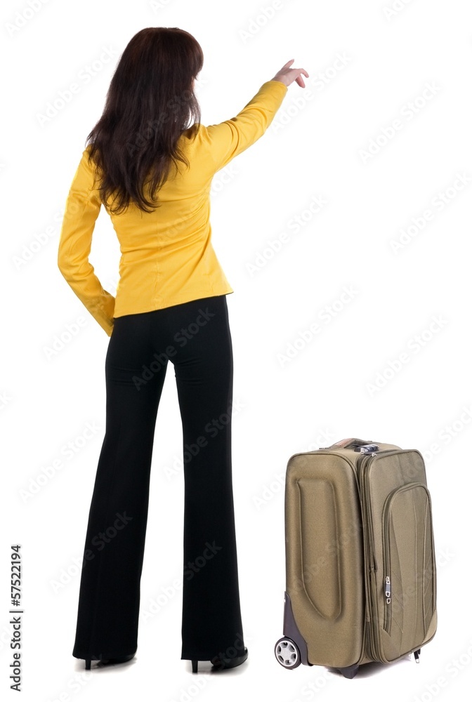 Young traveling woman with suitcas points at wall. Young traveling woman with suitcas points at wall.