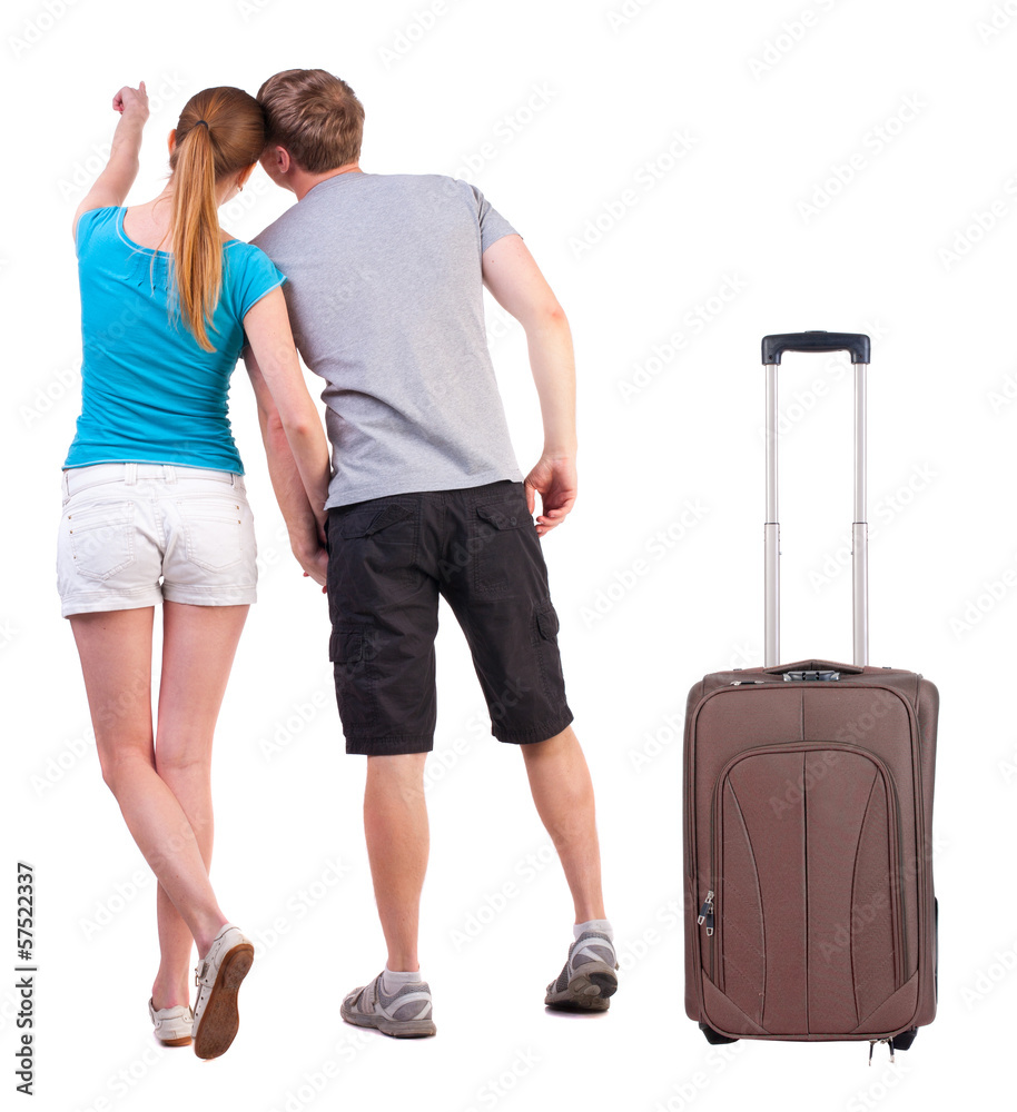 young couple traveling with suitcas and pointing at wal Back vie young couple traveling with suitcas and pointing at wal Back vie