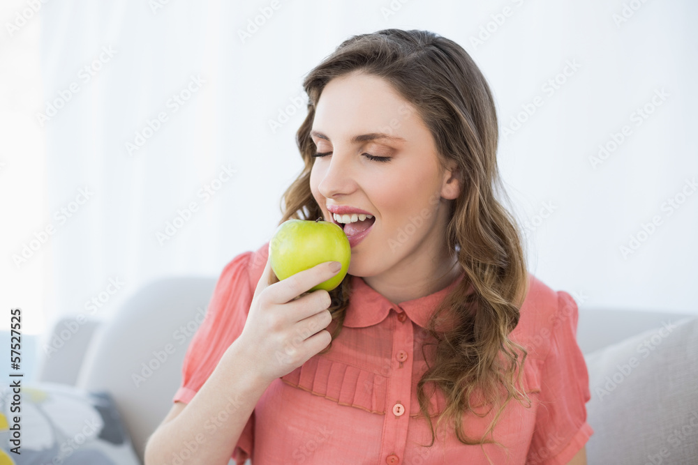 Enjoying pregnant woman eating green apple sitting on couch Enjoying pregnant woman eating green apple sitting on couch
