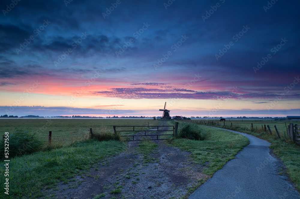Dutch windmill on meadow at sunrise