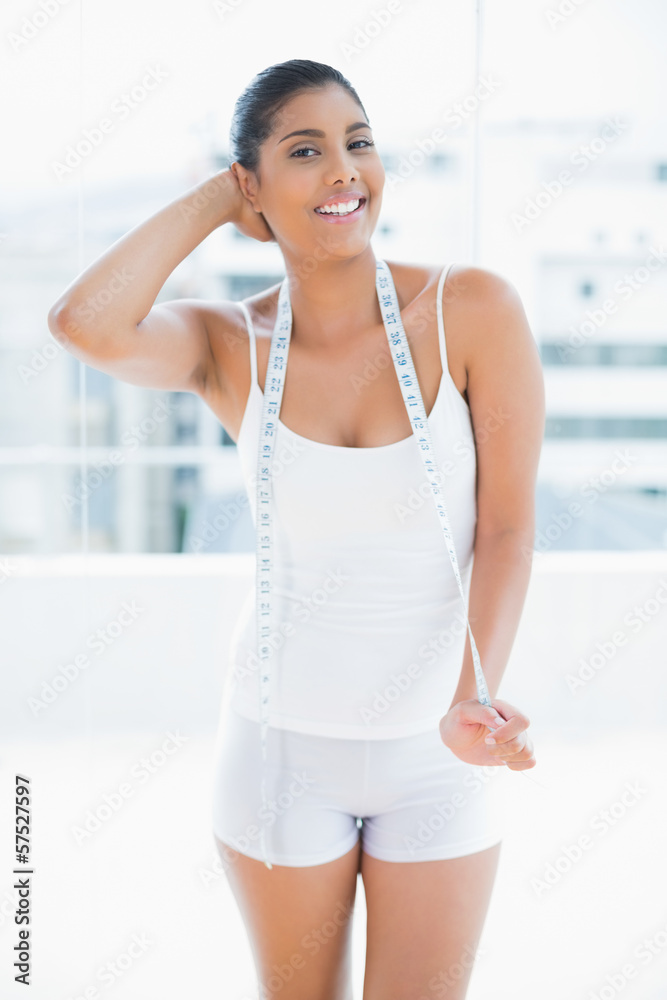 Happy toned brunette holding measuring tape