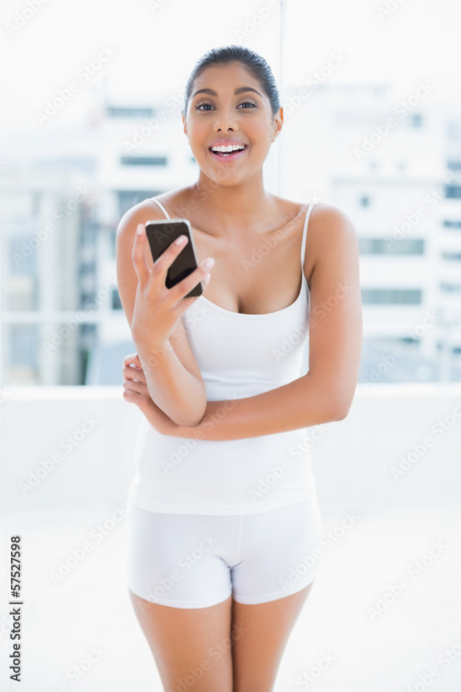 Cheerful toned brunette holding smartphone Cheerful toned brunette holding smartphone