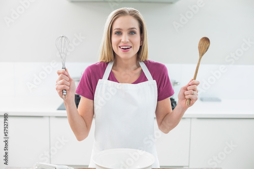 Fotografie Casual laughing blonde showing wooden spoon and whisk