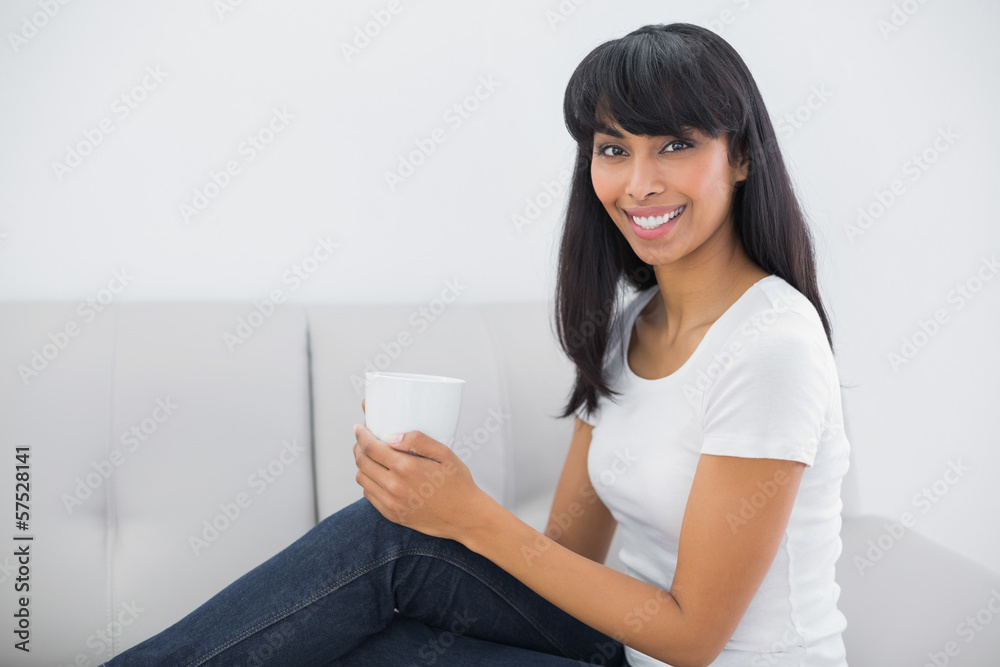 Relaxing young woman holding a cup sitting in bright living room Relaxing young woman holding a cup sitting in bright living room