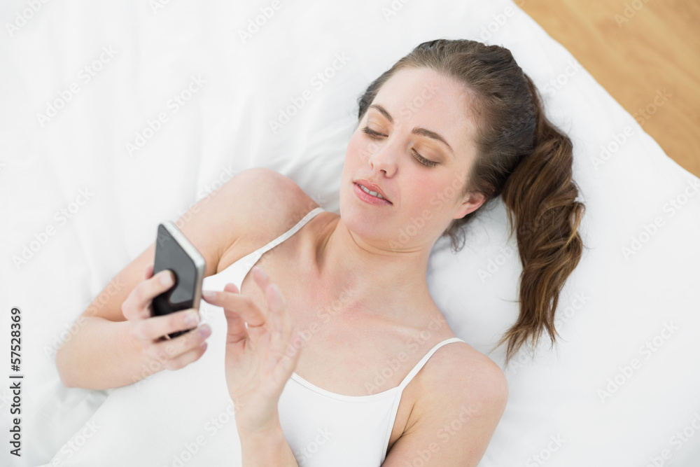 Relaxed woman using mobile phone in bed Relaxed woman using mobile phone in bed