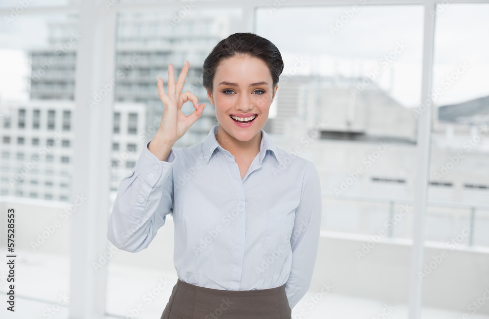 Elegant businesswoman gesturing ok sign in office Elegant businesswoman gesturing ok sign in office