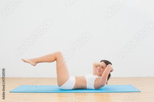Fototapeta Naklejka Na Ścianę i Meble -  Sporty woman doing sits up at fitness studio