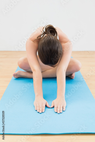 Sporty woman stretching hands on exercise mat